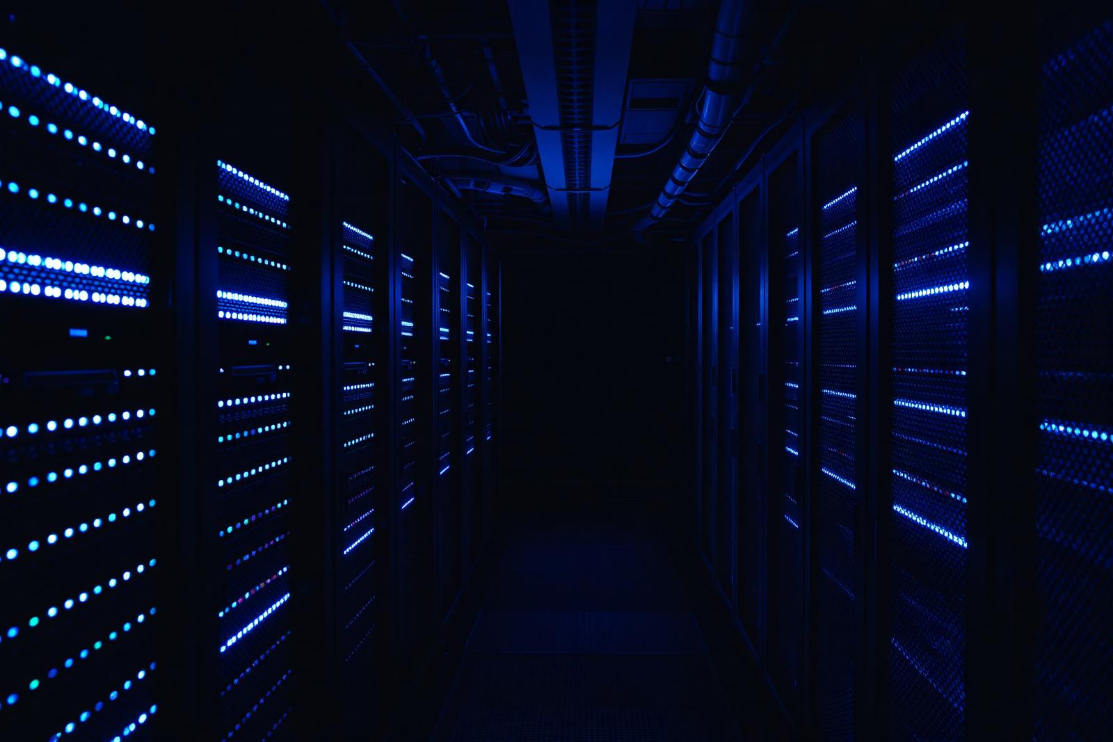 Rows of server racks in a data centre lit by cool blue indicator lights